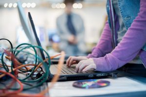 Persona trabajando con portátil, disco duro y cables de red